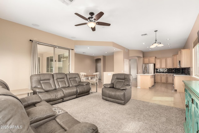 living area featuring arched walkways, light tile patterned floors, visible vents, and ceiling fan