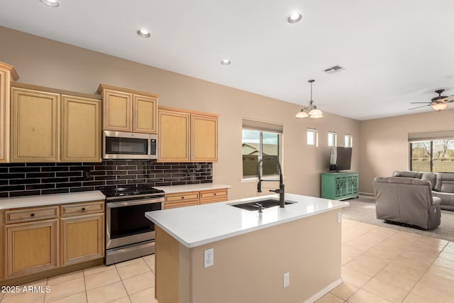 kitchen featuring open floor plan, light countertops, decorative backsplash, stainless steel appliances, and a sink