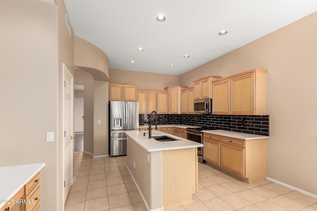 kitchen with light brown cabinets, appliances with stainless steel finishes, tasteful backsplash, and a sink