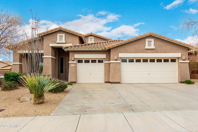 view of front facade with stucco siding, driveway, a tile roof, and a garage