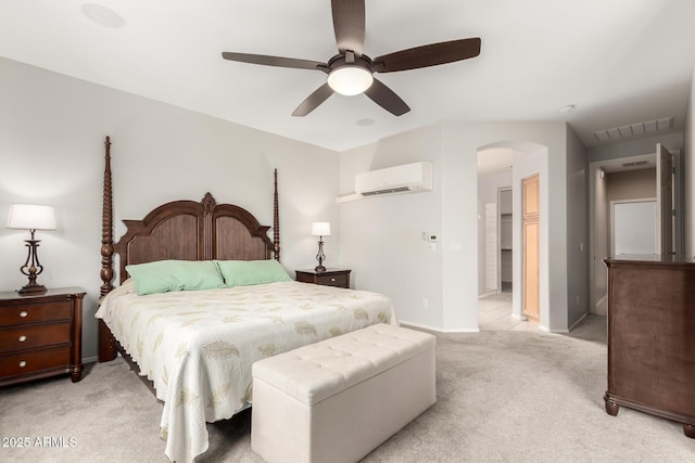 bedroom featuring baseboards, visible vents, a wall mounted AC, arched walkways, and light carpet