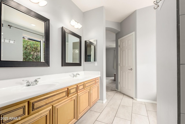 bathroom with double vanity, tile patterned floors, baseboards, and a sink