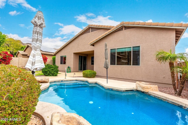 back of property with a patio area, stucco siding, an outdoor pool, and a tile roof