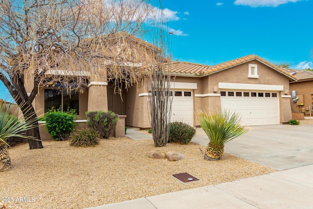 view of front of home with a tile roof, an attached garage, driveway, and stucco siding