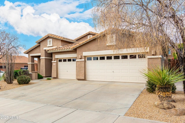 view of front facade with a tiled roof, a garage, driveway, and stucco siding