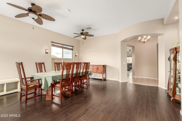 dining area with arched walkways, wood finished floors, and a ceiling fan