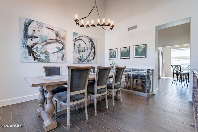 dining space with baseboards, visible vents, dark wood-style floors, a high ceiling, and a chandelier