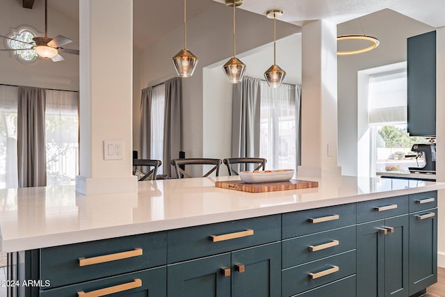 kitchen featuring lofted ceiling, light countertops, a ceiling fan, and decorative light fixtures