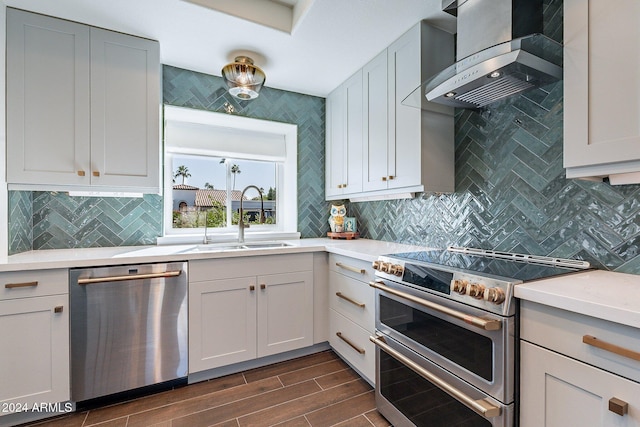 kitchen with wall chimney range hood, stainless steel appliances, a sink, and light countertops