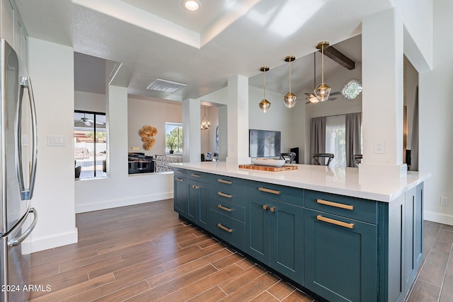 kitchen featuring light countertops, freestanding refrigerator, open floor plan, and wood finish floors