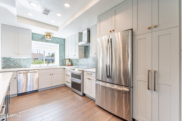 kitchen featuring wall chimney exhaust hood, visible vents, appliances with stainless steel finishes, and light countertops