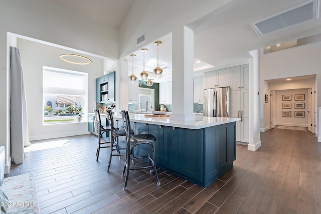 kitchen with freestanding refrigerator, visible vents, dark wood finished floors, and a peninsula