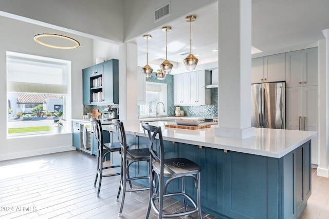 kitchen with visible vents, light countertops, freestanding refrigerator, and a healthy amount of sunlight