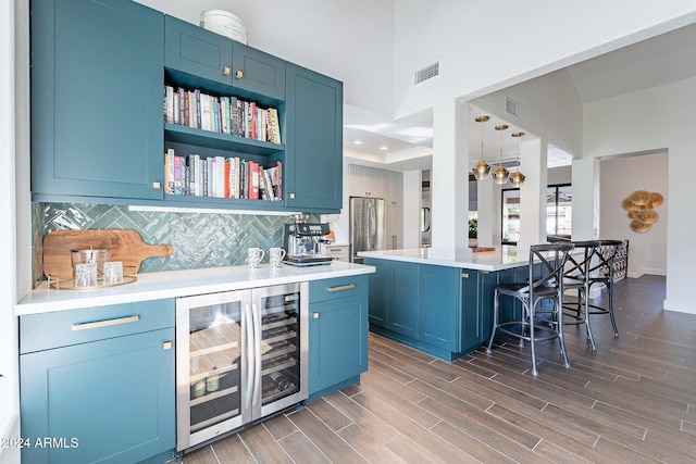 bar with visible vents, backsplash, wood tiled floor, freestanding refrigerator, and beverage cooler