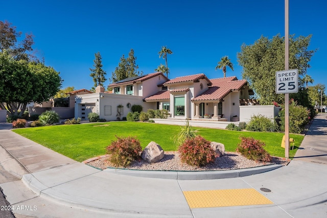 mediterranean / spanish-style home with a front lawn, fence, a tile roof, and stucco siding