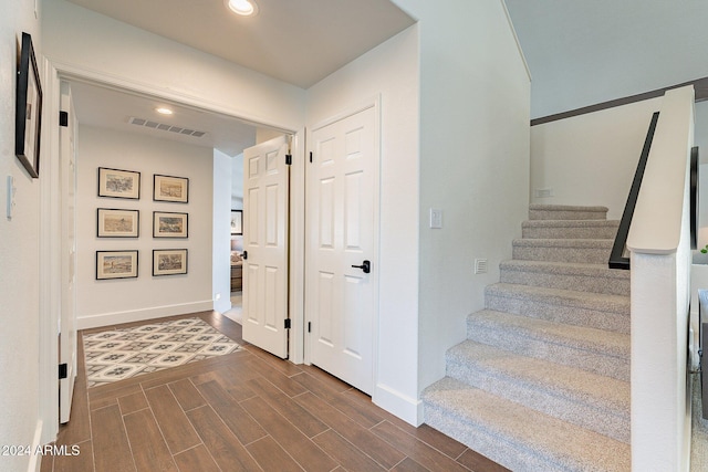 staircase with baseboards, wood finish floors, visible vents, and recessed lighting