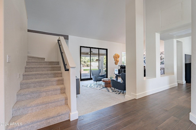 stairs with a towering ceiling, baseboards, and wood finished floors