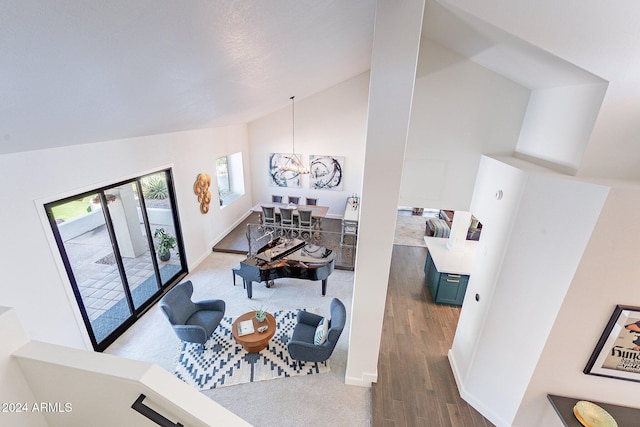 living area featuring high vaulted ceiling, baseboards, an inviting chandelier, and wood finished floors