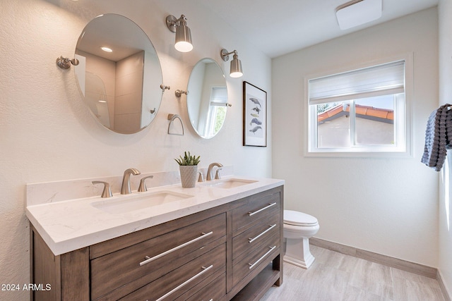 full bath with baseboards, a sink, toilet, and double vanity