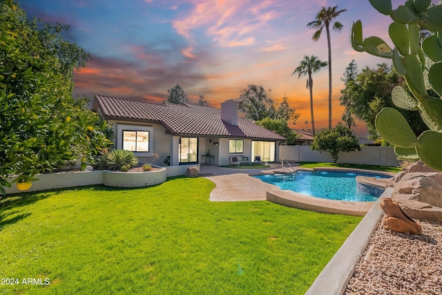 pool at dusk featuring a fenced in pool, a fenced backyard, a yard, and a patio