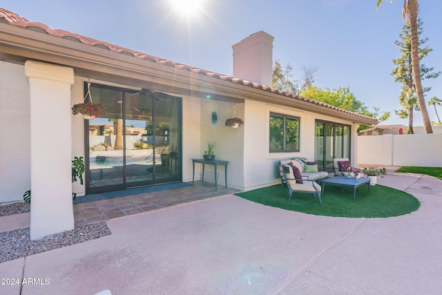 exterior space featuring a patio, a tile roof, fence, stucco siding, and a chimney