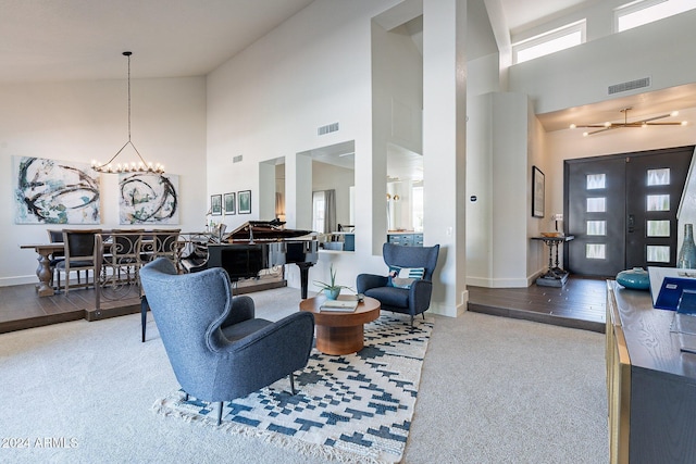 living area featuring visible vents, a notable chandelier, and a towering ceiling