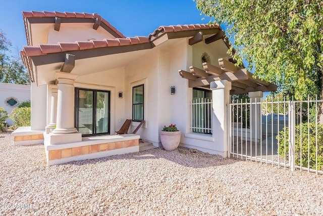 back of property with a tiled roof and stucco siding