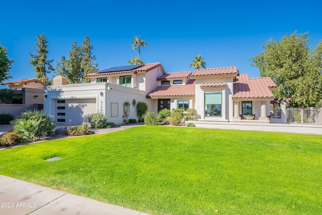 mediterranean / spanish home featuring a garage, a tiled roof, a front yard, and stucco siding