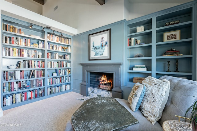 sitting room featuring visible vents, a fireplace with flush hearth, carpet, vaulted ceiling, and built in shelves