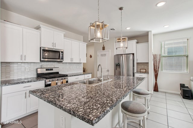 kitchen featuring an island with sink, sink, appliances with stainless steel finishes, white cabinets, and pendant lighting