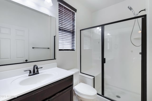 bathroom featuring vanity, a shower with shower door, and toilet