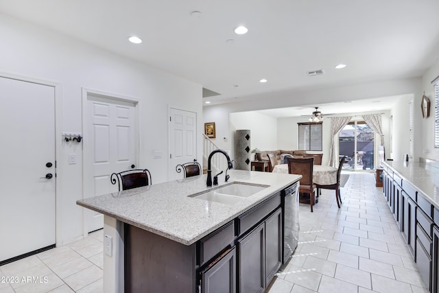 kitchen with ceiling fan, sink, dishwashing machine, a kitchen island with sink, and light tile patterned floors