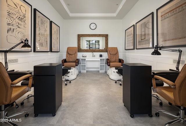 home office with a decorative wall, a raised ceiling, and wainscoting