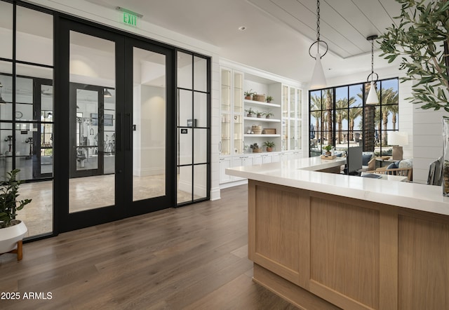 interior space featuring french doors, dark hardwood / wood-style floors, hanging light fixtures, and light brown cabinets