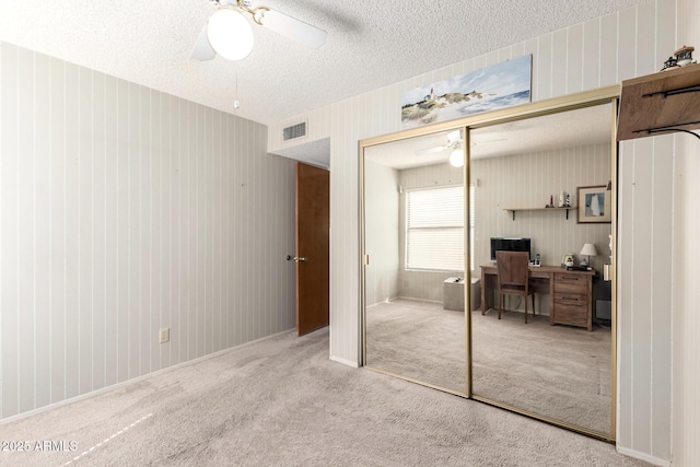 bedroom featuring carpet floors, a closet, visible vents, a ceiling fan, and a textured ceiling