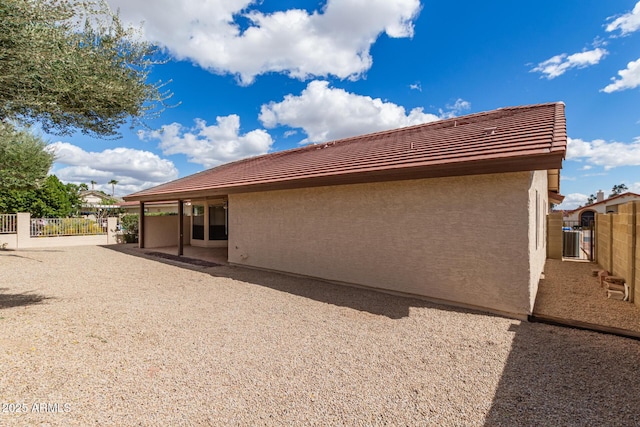 view of side of property with a patio, fence, and stucco siding