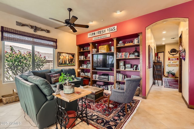 living area with light tile patterned floors, arched walkways, and a ceiling fan