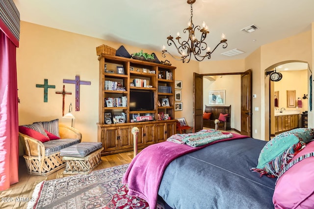 bedroom with arched walkways, visible vents, an inviting chandelier, and wood finished floors
