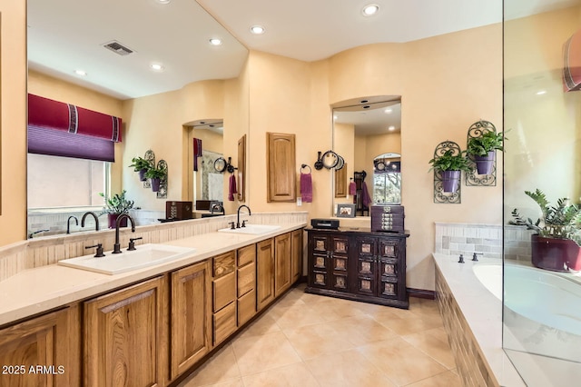 bathroom with tile patterned floors, visible vents, a sink, and a garden tub