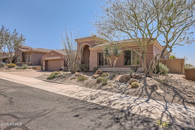 mediterranean / spanish home with driveway, fence, a tiled roof, a garage, and stucco siding