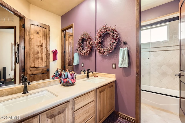 full bath with double vanity, a sink, shower / bath combination with glass door, and tile patterned floors