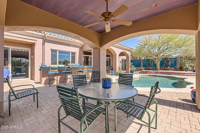 view of patio / terrace with a fenced in pool, outdoor dining area, outdoor dry bar, and ceiling fan