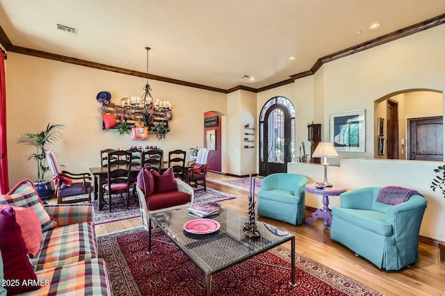 living room with arched walkways, visible vents, an inviting chandelier, and wood-type flooring