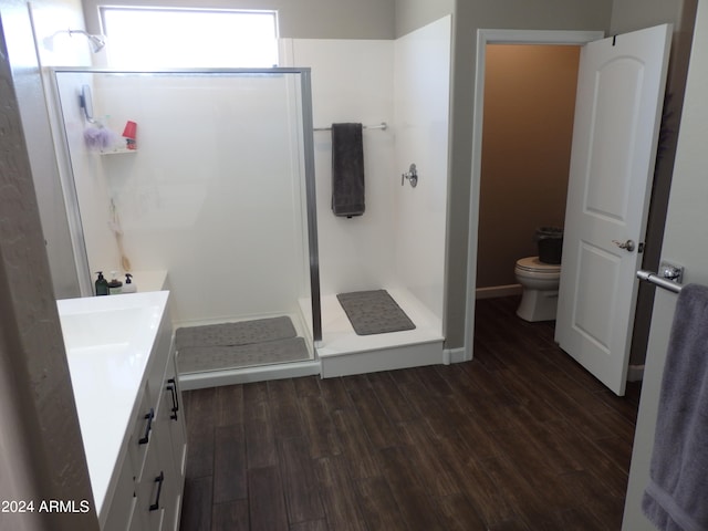 bathroom featuring vanity, a shower with shower door, wood-type flooring, and toilet