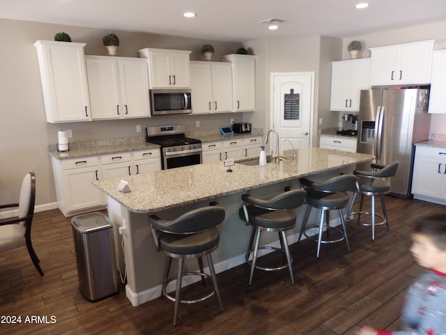 kitchen with a kitchen island with sink, sink, white cabinets, appliances with stainless steel finishes, and dark hardwood / wood-style flooring