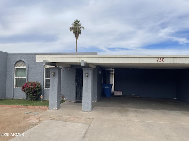 exterior space with concrete driveway, an attached carport, and stucco siding