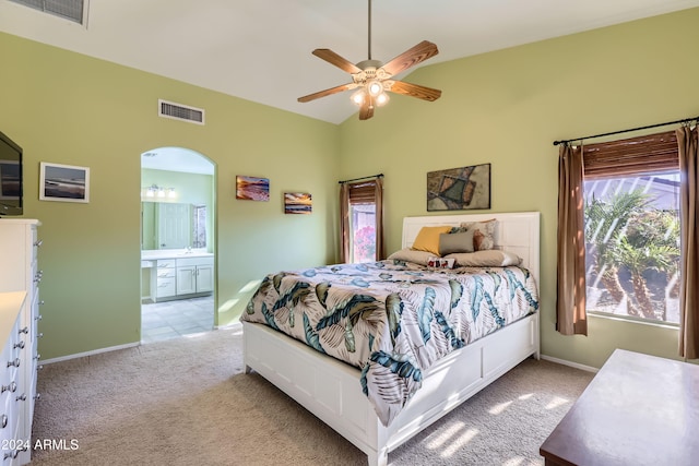 bedroom with ceiling fan, lofted ceiling, light carpet, and connected bathroom