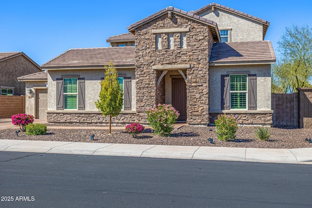 view of front of property featuring stucco siding, stone siding, a tile roof, and fence