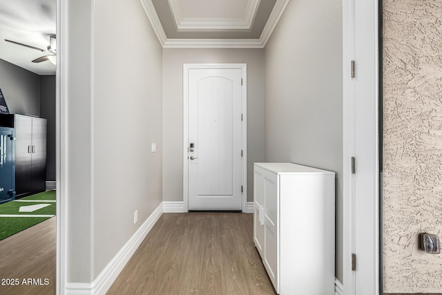 doorway to outside featuring crown molding, a ceiling fan, baseboards, and light wood finished floors