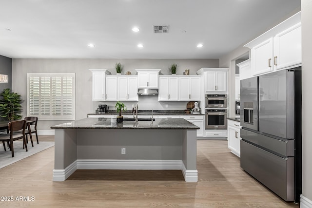 kitchen featuring under cabinet range hood, visible vents, light wood-style floors, and appliances with stainless steel finishes
